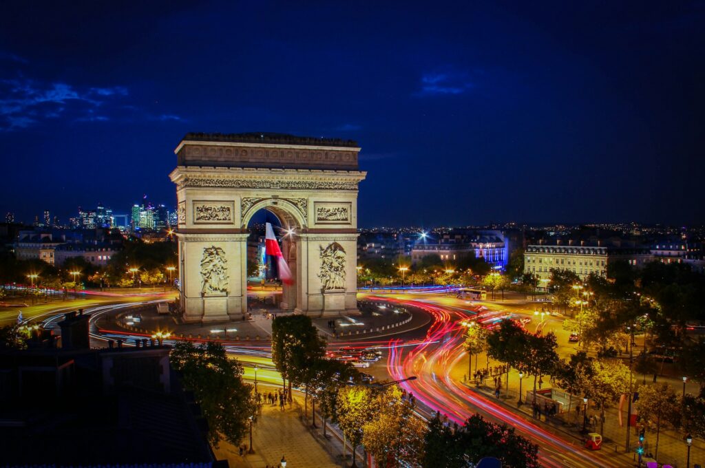 The majestic Arc de Triomphe standing tall at the heart of Paris, adorned with intricate sculptures and illuminated by soft evening lights. The grand monument, built to honor France’s military victories, is surrounded by the bustling Champs-Élysées. A must-see landmark for travelers exploring historical sites in Paris
